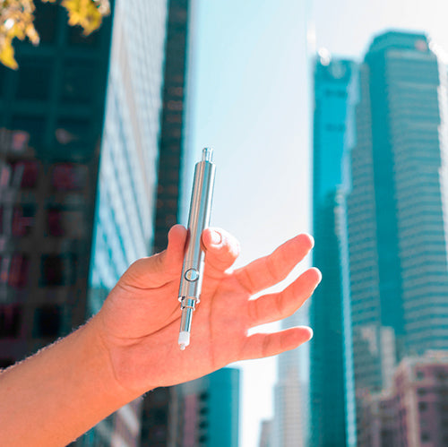 Linx Ares Dab Straw Held in Hand In Front of Large Buildings Blue