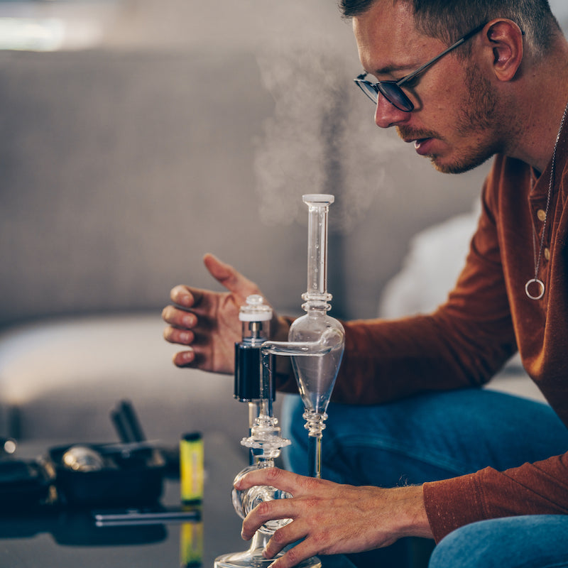 Linx Apollo Electric Dab Rig and E Nail in Desktop mode with E Nail on glass Dab Rig in use by a man in an orange shirt on a couch 