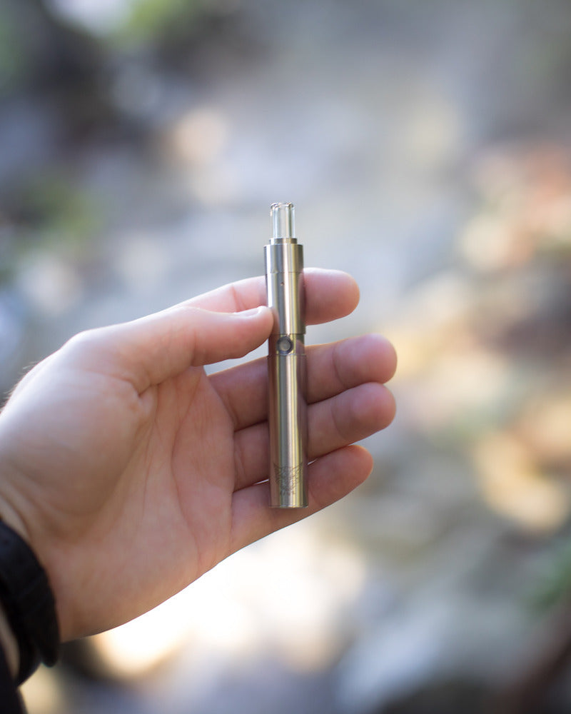 One of the best dab pens, the Linx-Hypnos Zero Concentrate Vaporizer is held in hand outdoors with blurred background 